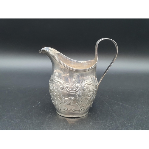 9 - A George III silver oval Jug with floral and scroll embossing, engraved crest, London 1803