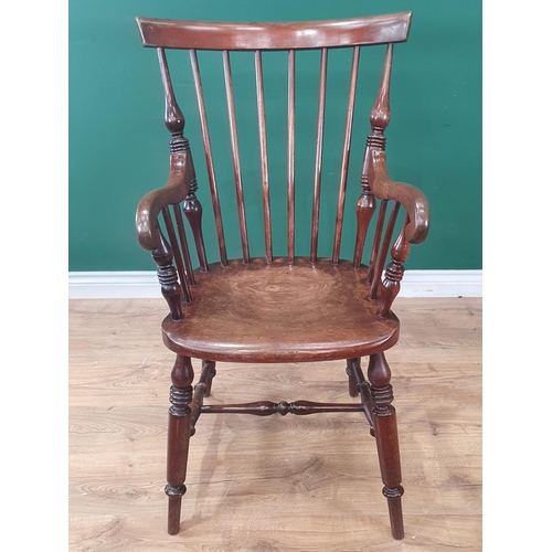 900 - A 19th Century mahogany Windsor Elbow Chair with comb and stick back raised on turned supports unite... 