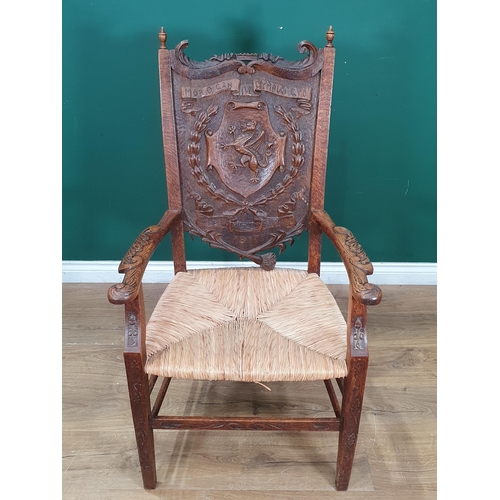 908 - A carved oak Eisteddfod Elbow Chair the back carved with dragon in a panel and dated 1917, with rush... 