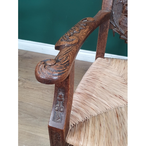 908 - A carved oak Eisteddfod Elbow Chair the back carved with dragon in a panel and dated 1917, with rush... 