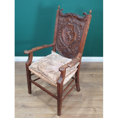 908 - A carved oak Eisteddfod Elbow Chair the back carved with dragon in a panel and dated 1917, with rush... 