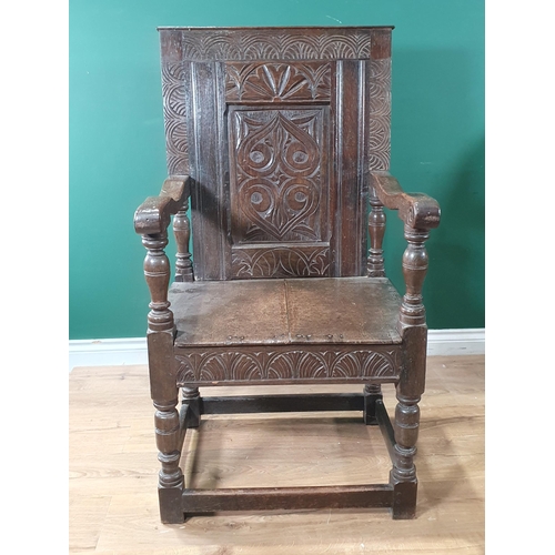 909 - An antique oak Wainscot Elbow Chair with carved and panelled back, carved seat rail on turned suppor... 