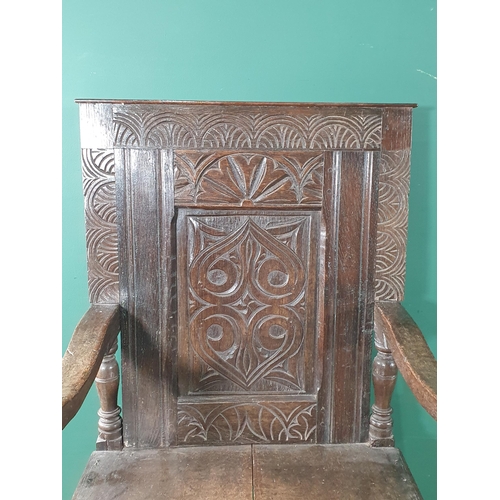 909 - An antique oak Wainscot Elbow Chair with carved and panelled back, carved seat rail on turned suppor... 