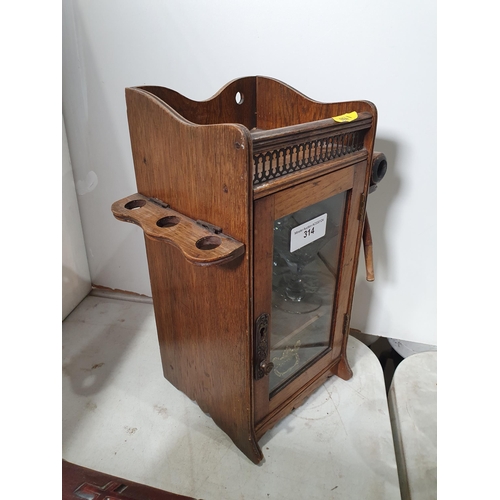 314 - An oak Smoker's Table Cabinet with glazed door and complete with three pipes (R5)