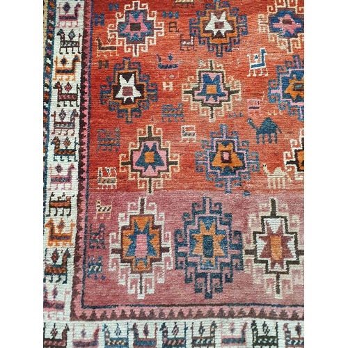 342 - A North African woollen Rug with stylised flower heads on red ground within multiple borders decorat... 