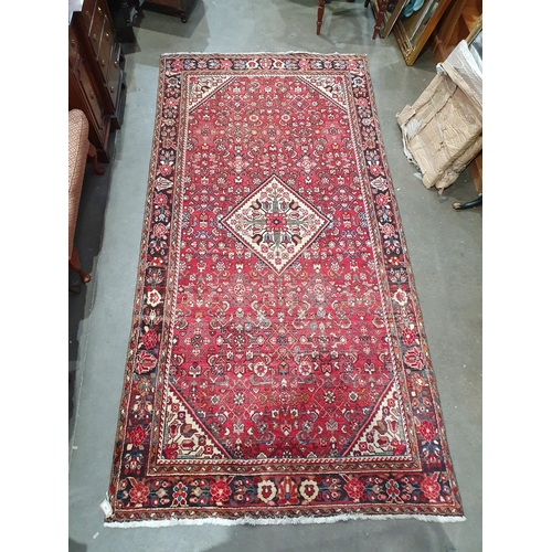 745 - A Persian Rug with floral motifs to the borders and central floral lozenge on a red ground, 10ft 2in... 