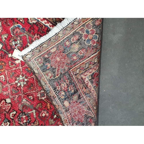 745 - A Persian Rug with floral motifs to the borders and central floral lozenge on a red ground, 10ft 2in... 