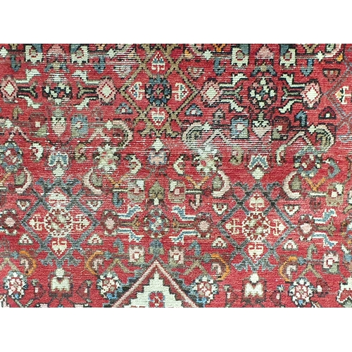 745 - A Persian Rug with floral motifs to the borders and central floral lozenge on a red ground, 10ft 2in... 