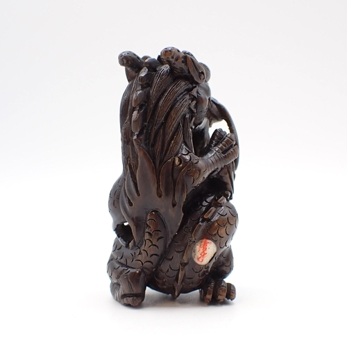 211 - A finely carved wooden Dragon Netsuke with inlaid signature, 5cms high