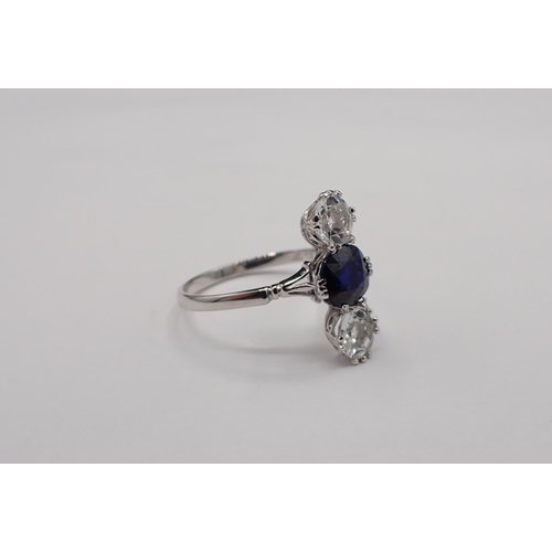 154 - A three stone Ring claw-set oval-cut sapphire between two round white stones in white metal, marks r... 