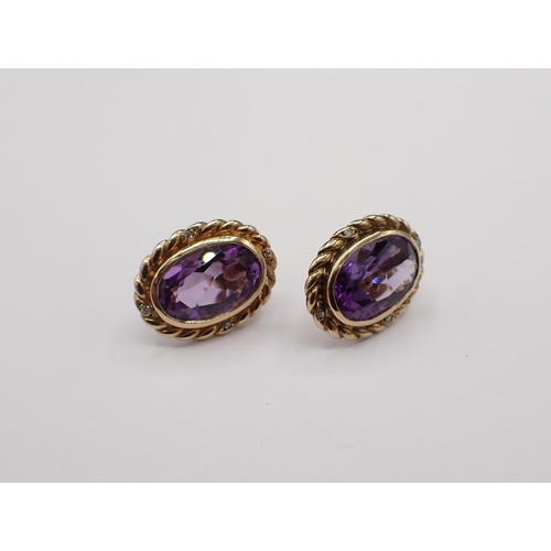 159 - A pair of Amethyst and Diamond Earrings each rubover-set large oval-cut amethyst in rope twist frame... 