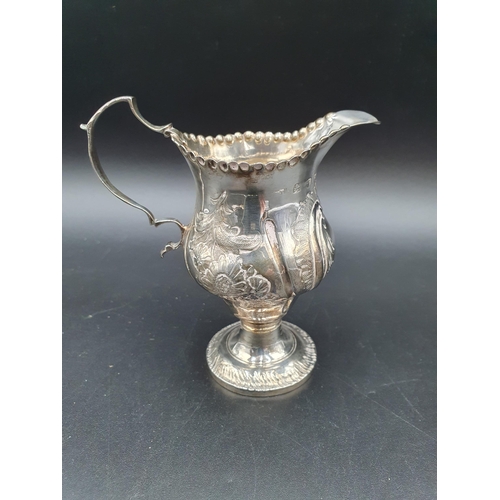 131 - A George III silver Cream Jug with later floral embossing on pedestal base, London circa 1770