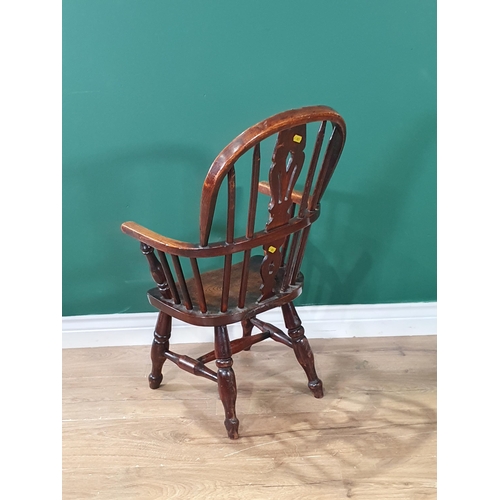 24 - An antique ash and elm child's Windsor Elbow Chair with pierced splat back, and raised on turned sup... 