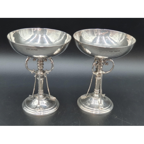 285 - A near pair of George V silver Golfing Trophies with hammered bowls on three scroll and golf club su... 