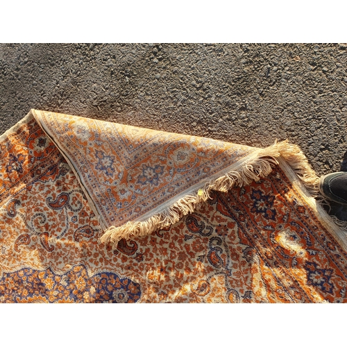 606 - An orange and beige ground Rug with multi-borders with large central floral decorated lozenge, 106in... 