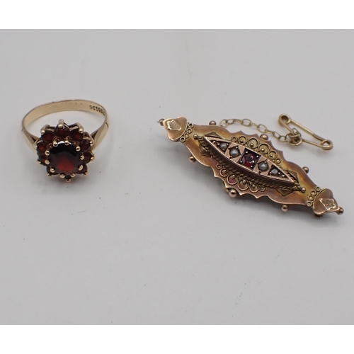 170 - A Garnet Cluster Ring peg-set oval-cut stone within a frame of smaller round stones, stamped 9ct, ri... 