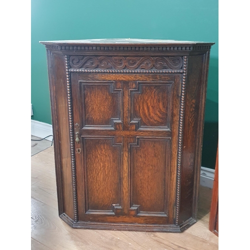 498 - An oak Hanging Corner Cupboard with carved frieze above single panel door, 2ft 7