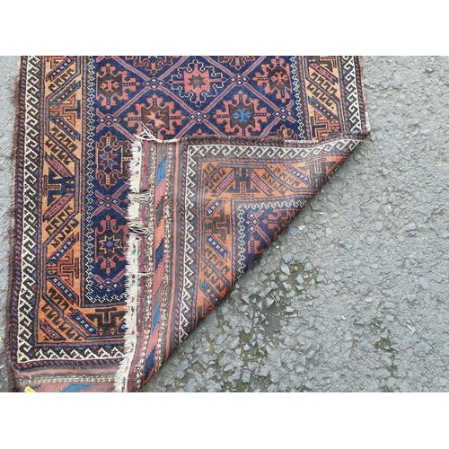 62 - A bordered Afghan Rug with trellis snowflake design in claret and blue, latch hook outer border in c... 