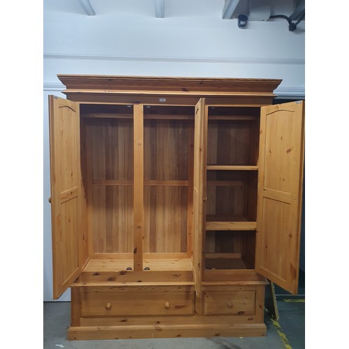 48 - A pine Wardrobe with three doors enclosing hanging space and shelves, above two drawers, 6ft 8in H x... 