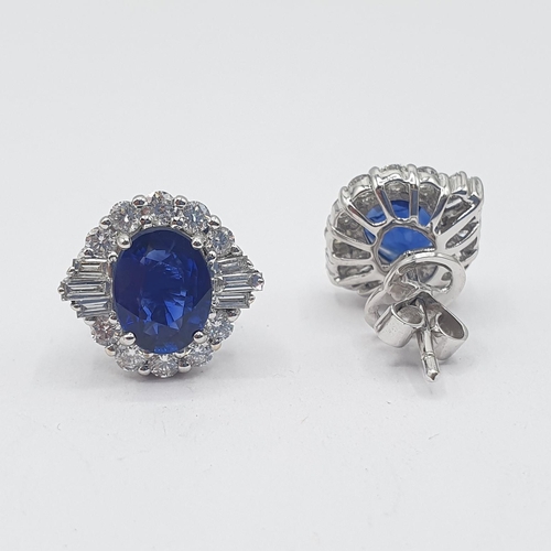 214 - A pair of Sapphire and Diamond Cluster Earrings each claw-set oval-cut sapphire within a frame of ba... 