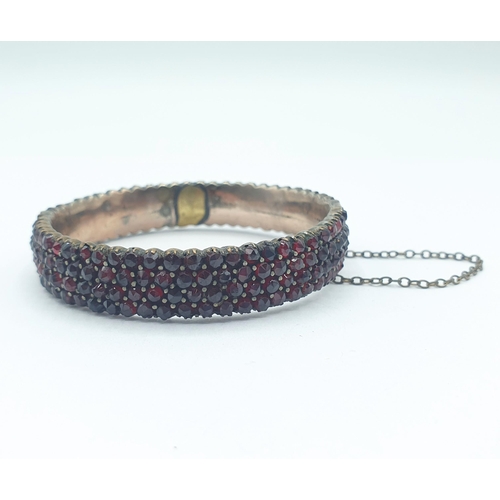 221 - A Garnet set hinged Bangle peg-set numerous rose-cut stones