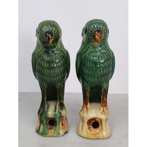 301 - A near pair of Chinese Sancai style green crackle glazed Parrots upon pierced tree stump supports, 6... 