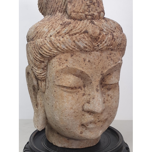 311 - A carved stone Buddha Head with later carved wooden associated Stand. A/F. (Head alone measures 11