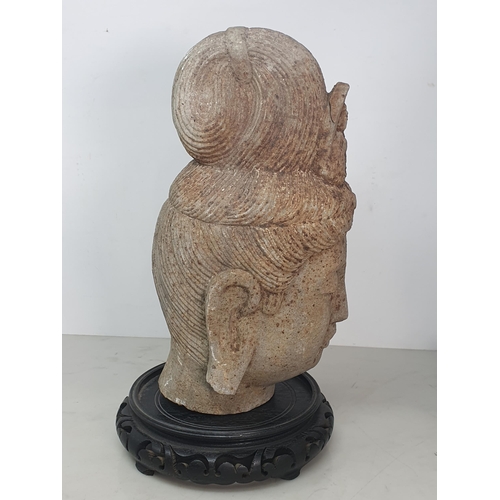 311 - A carved stone Buddha Head with later carved wooden associated Stand. A/F. (Head alone measures 11