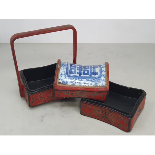 313 - A Chinese three tier lacquered Tiffin Carrier, the lid with inset blue and white tile, with red lacq... 