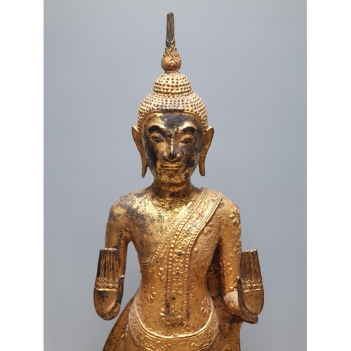 318 - A 19th Century gilt bronze Figure of a Buddha, wearing robes with all over floral/star decorations, ... 