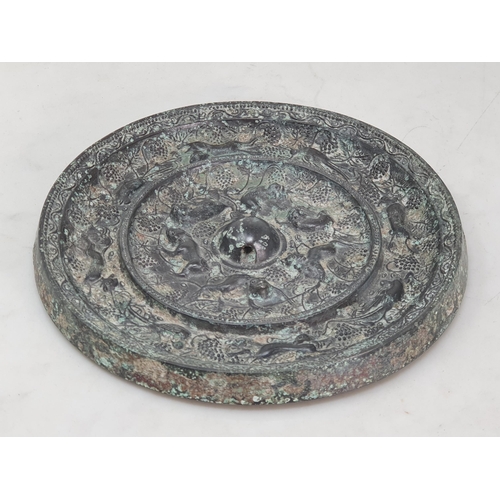 320 - A patinated Chinese bronze circular Mirror/Roundel with fruiting vine, bird and beast border, the ce... 