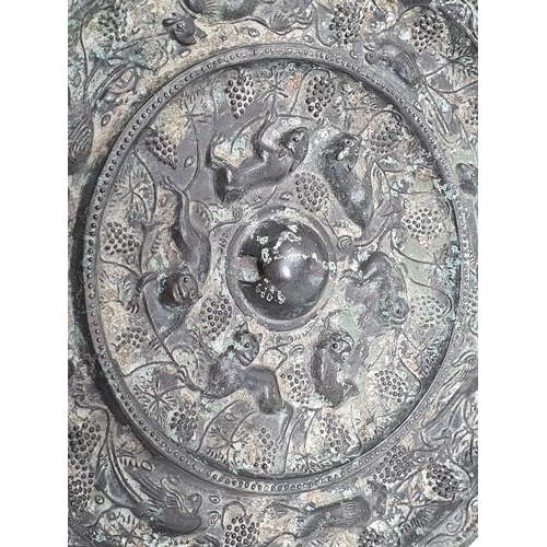 320 - A patinated Chinese bronze circular Mirror/Roundel with fruiting vine, bird and beast border, the ce... 