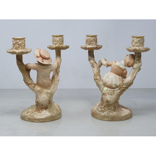 387 - A pair of Royal Worcester Hadley two branch blush Candelabra with figures of boy and girl on branch ... 