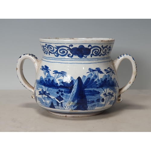 393 - A Delft blue and white two handled Posset Pot with scrolled frieze with Chinese Chinoiseries Landsca... 