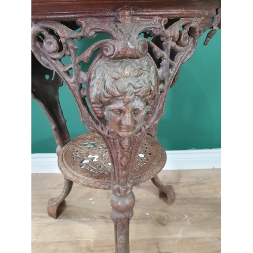 469 - A cast iron Garden Table with circular wooden top with masks to the supports and with lower tier, 22... 