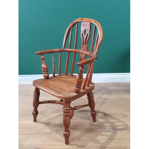 492 - An ash and yew child's Windsor Armchair with pierced splat back raised on turned supports united by ... 