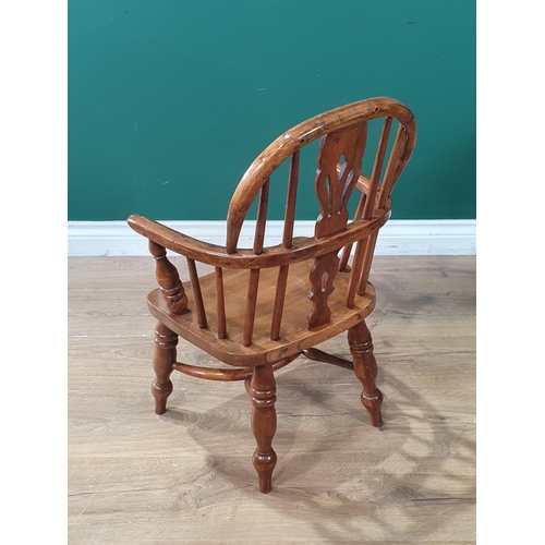 492 - An ash and yew child's Windsor Armchair with pierced splat back raised on turned supports united by ... 