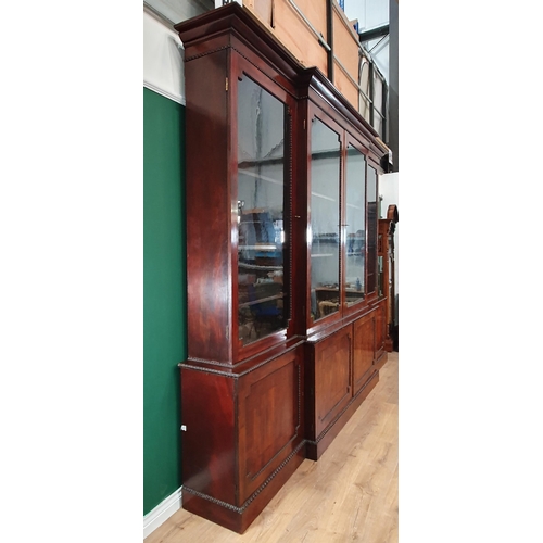 509 - A Regency flame mahogany Breakfront Bookcase, the moulded cornice above four glazed doors enclosing ... 