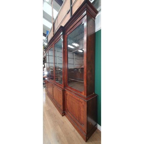 509 - A Regency flame mahogany Breakfront Bookcase, the moulded cornice above four glazed doors enclosing ... 