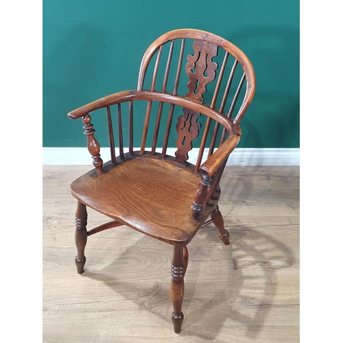 566 - A 19th Century ash and yew Windsor Elbow Chair with pierced splat back raised on turned supports uni... 