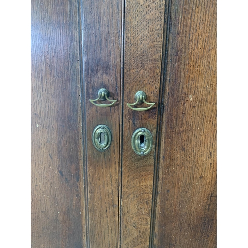 580 - An 18th Century oak Bacon Cupboard with pair of cupid's bow panelled doors above panelled doors, 5ft... 