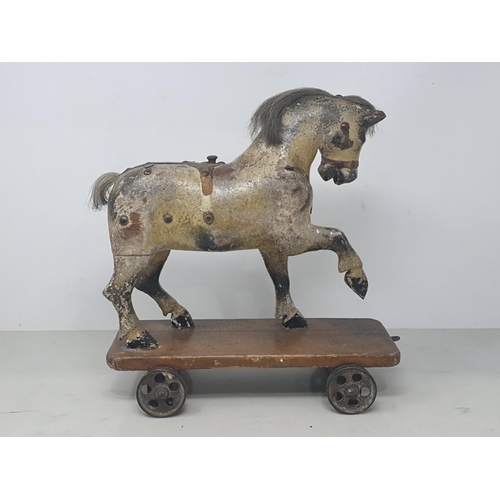 642 - An antique carved and dapple painted pull along Horse on stained wooden base with metal wheels 11in ... 