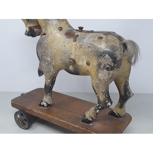 642 - An antique carved and dapple painted pull along Horse on stained wooden base with metal wheels 11in ... 