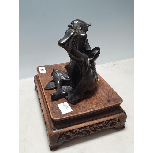 306 - A Chinese bronze Sculpture of a man in robes falling over, on associated hardwood Stand 6 1/2in H