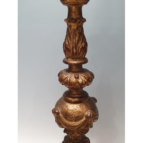 512 - An 18th Century giltwood Candlestick with cherub mask and leafage and scrolled designs, raised on th... 