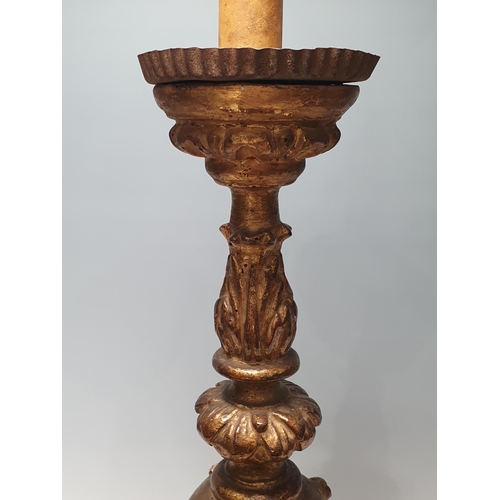 512 - An 18th Century giltwood Candlestick with cherub mask and leafage and scrolled designs, raised on th... 