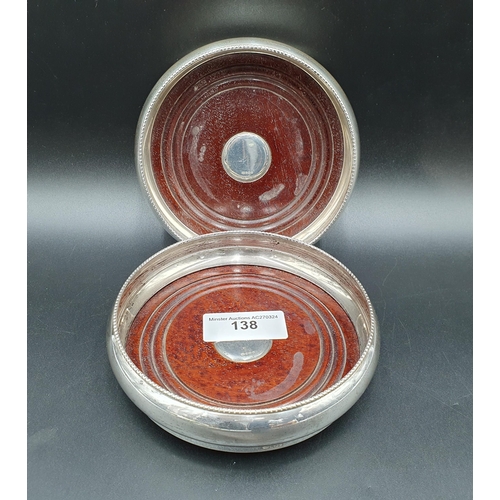 138 - A pair of Elizabeth II silver circular Coasters with beaded rims, mahogany bases with silver centres... 