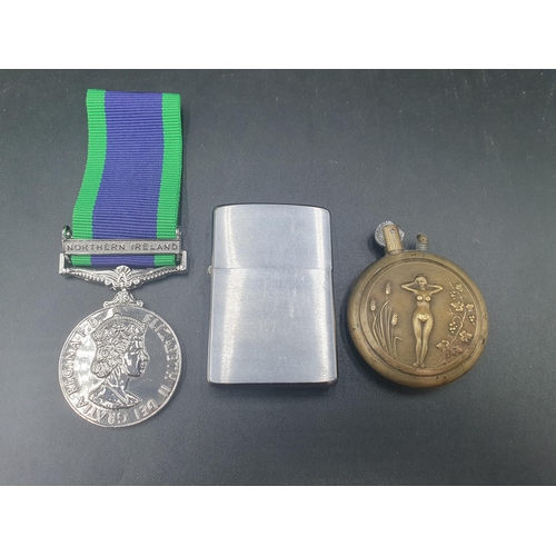 95 - A reproduction Northern Ireland Campaign Medal, a Trench Art Lighter and a Zippo Lighter