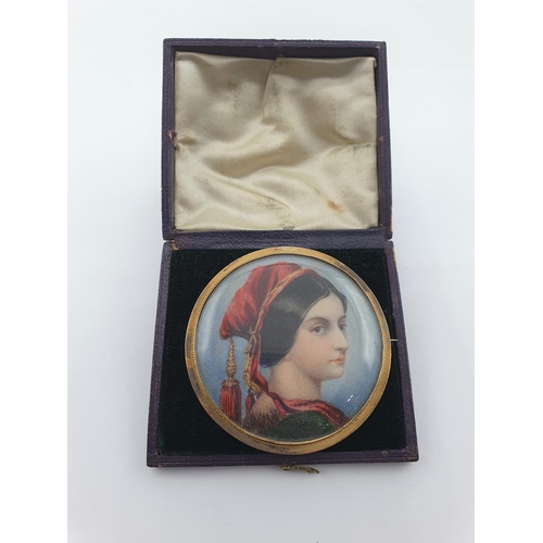 174 - A painted Portrait Miniature Brooch of lady in red hat with tassel, in yellow metal frame, 5.5cms di... 