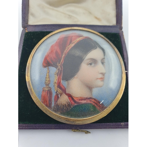 174 - A painted Portrait Miniature Brooch of lady in red hat with tassel, in yellow metal frame, 5.5cms di... 